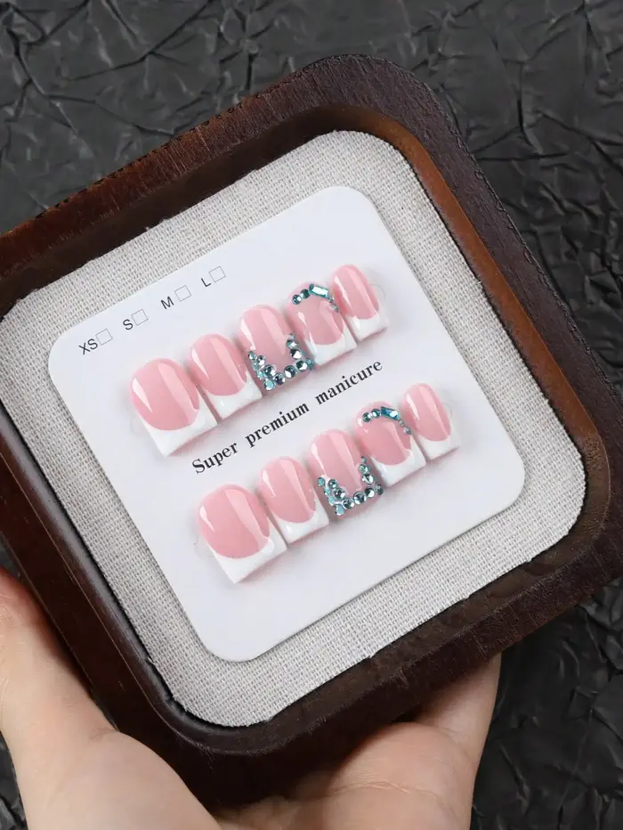 10 faux ongles courts rectangulaires faits à la main, au style français doux et frais, couleur de base rose nude propre avec des bords français blancs, ornements délicats en strass bleus, texture de h
