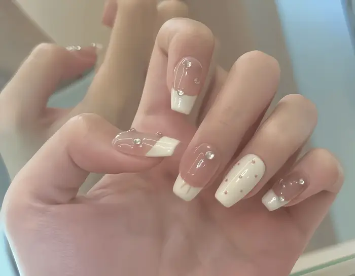10 pièces d'ongles artificiels faits à la main, à couverture complète, de longueur moyenne, couleur nude avec pointes françaises blanc laiteux, petites points rouges et embellissements délicats en str