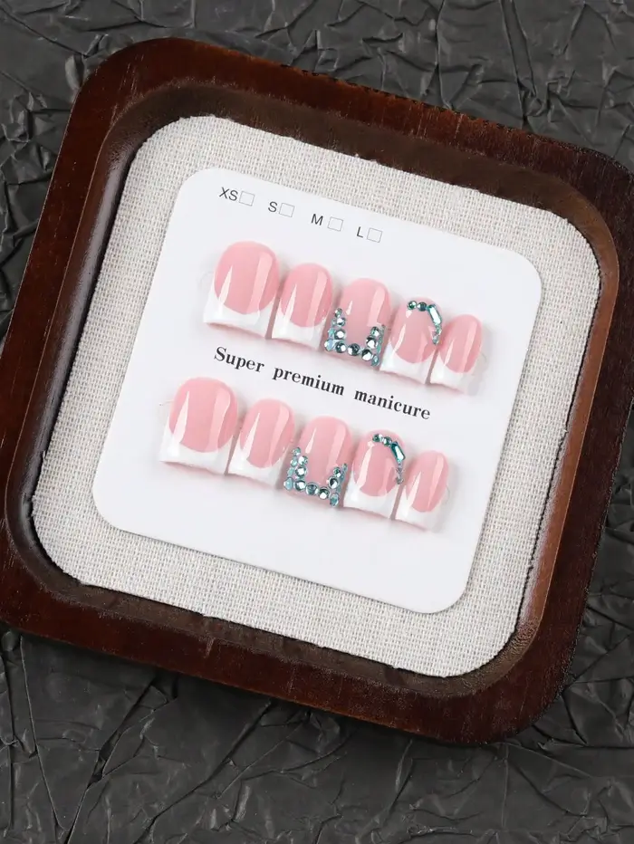 10 faux ongles courts rectangulaires faits à la main, au style français doux et frais, couleur de base rose nude propre avec des bords français blancs, ornements délicats en strass bleus, texture de h