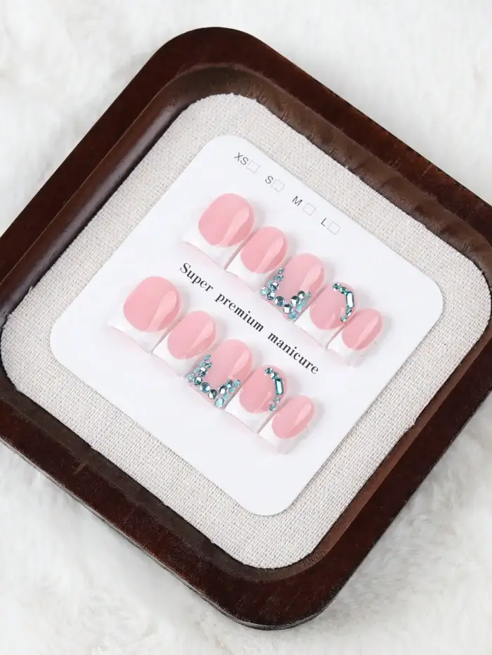 10 faux ongles courts rectangulaires faits à la main, au style français doux et frais, couleur de base rose nude propre avec des bords français blancs, ornements délicats en strass bleus, texture de h
