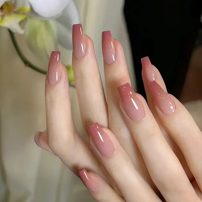 Un ensemble complet de 24 faux ongles moyens en forme de cercueil avec un design dégradé pêche