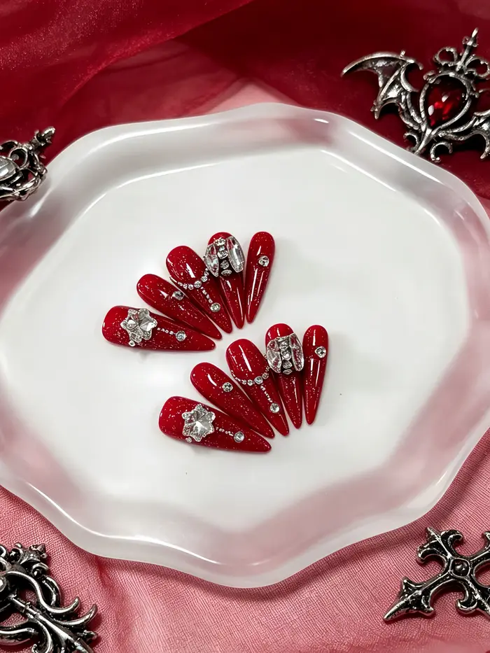 10 faux ongles longs en forme de larme, avec une base rouge pailletée, décorés de strass en forme de