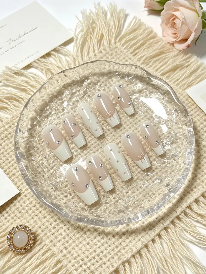 10 faux ongles trapézoïdaux de longueur moyenne, principalement en blanc laiteux et rose nude, avec 