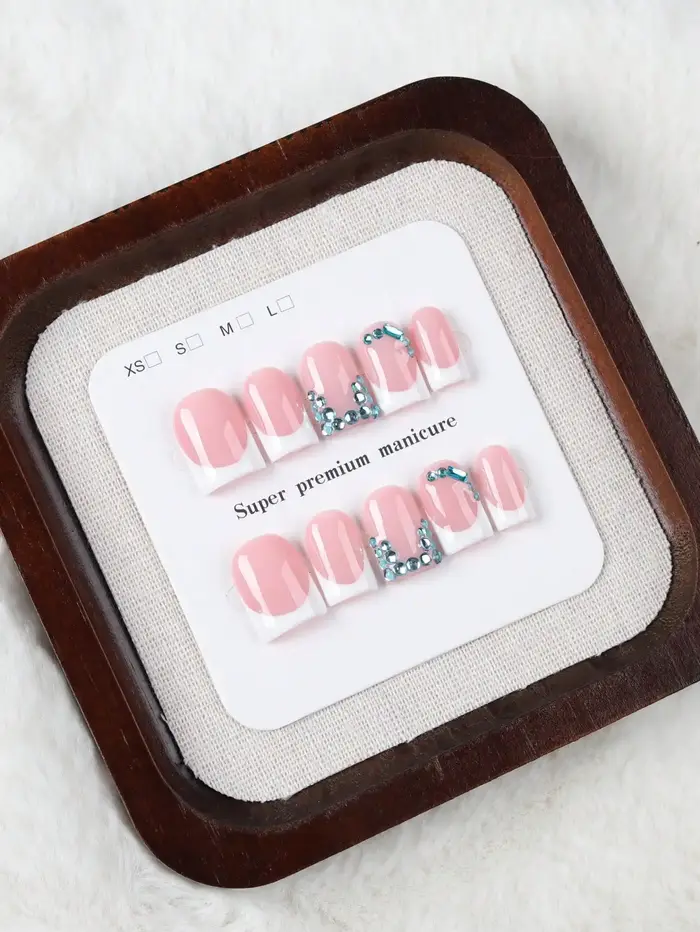 10 faux ongles courts rectangulaires faits à la main, au style français doux et frais, couleur de base rose nude propre avec des bords français blancs, ornements délicats en strass bleus, texture de h