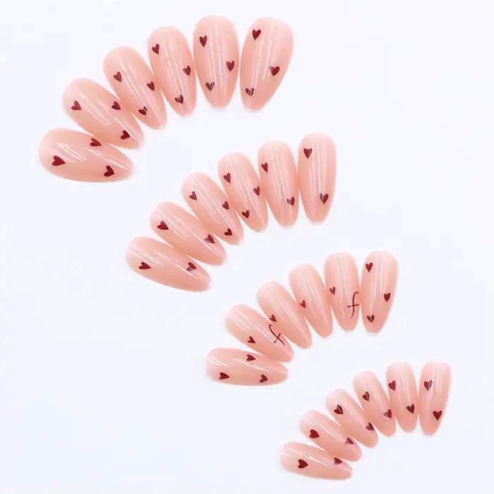 24 faux ongles en acrylique français pressés avec des motifs en forme de cœur et de lettres.