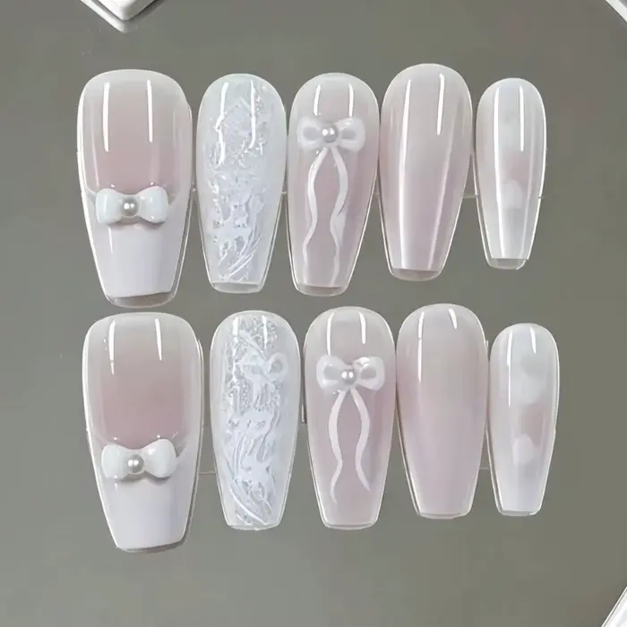 10 faux ongles de longueur moyenne, avec une base dégradée rose nude et blanc laiteux, ornés d'une t